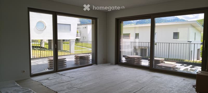 Empty room with large sliding glass doors leading to a balcony, covered floor, and a scenic mountain view outside.