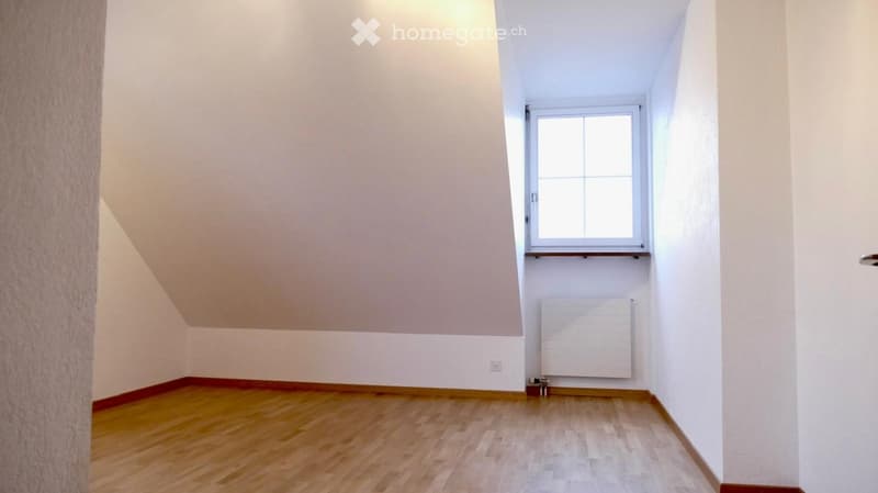 Empty room with wooden flooring, white walls, and a window with white frame. No furniture or equipment present.
