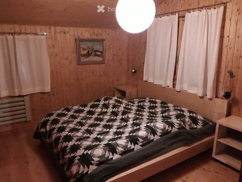 Cozy wooden bedroom with a single bed, nightstand, and a picture frame on the wall.