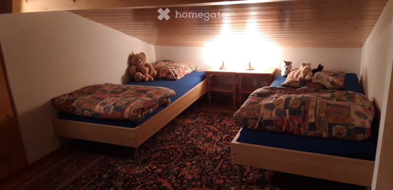 Cozy bedroom with two single beds, colorful bedding, nightstands, and stuffed toys.
