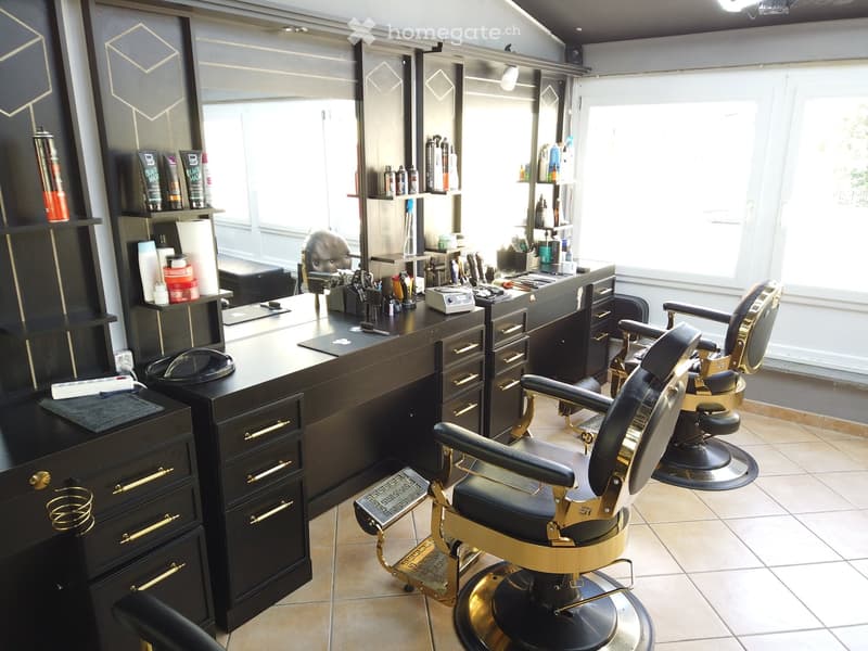Modern salon with two barber chairs, a large mirror, shelves with hair products, and a cabinet with drawers.