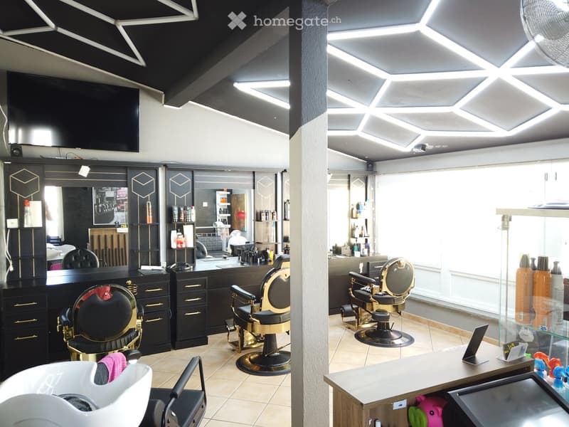 Modern salon with sleek black and gold styling chairs, mirrors, shelves with hair products, and a reception counter.