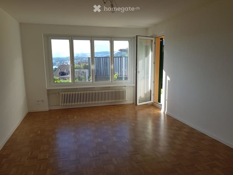 Unfurnished Room. Empty room with wooden flooring, large windows offering a view, radiator, and an open door leading to another space.