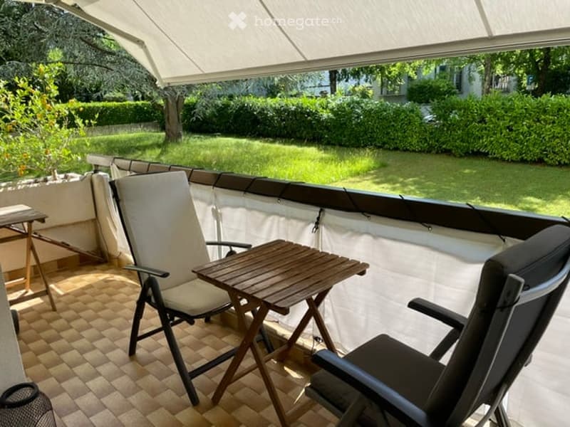 Balcony with a white canopy, tiled floor, and outdoor furniture including a table and chairs.