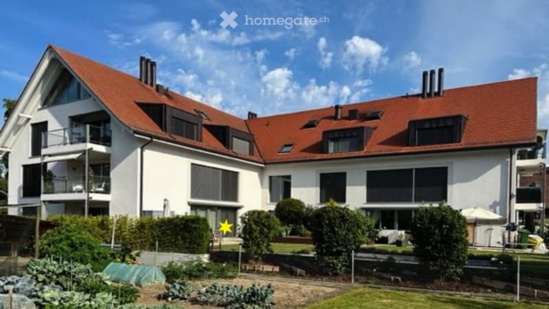 Modern two-story house with white exterior, red-tiled roof, multiple balconies, and well-maintained garden area.