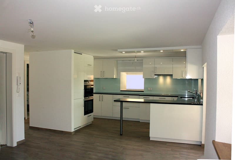 Modern kitchen with white cabinets, stainless steel appliances, and a central island with a black countertop.