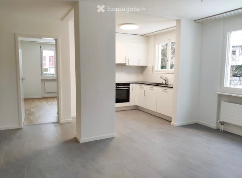 Modern kitchen with white cabinets, a sink, a faucet, and an oven. The space is bright with large windows and a clean, minimalist design.