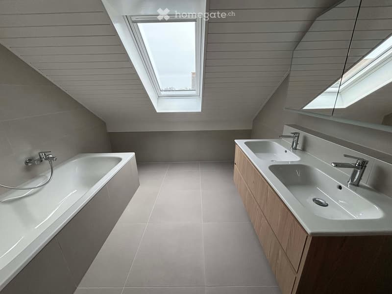 Bathroom. Modern bathroom with a large bathtub, double sink, sleek wooden cabinetry, and skylight windows providing natural light.