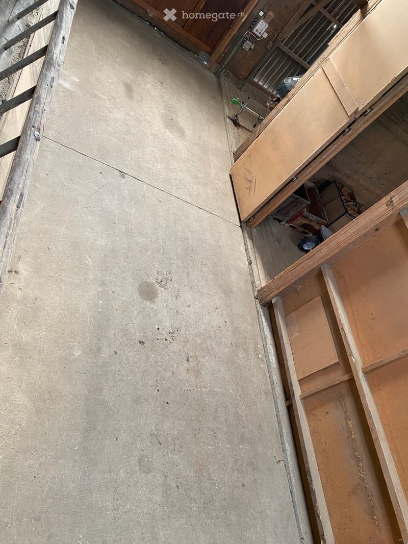 Empty room with exposed concrete walls and wooden framing, showing unfinished construction with no furniture or furnishings.