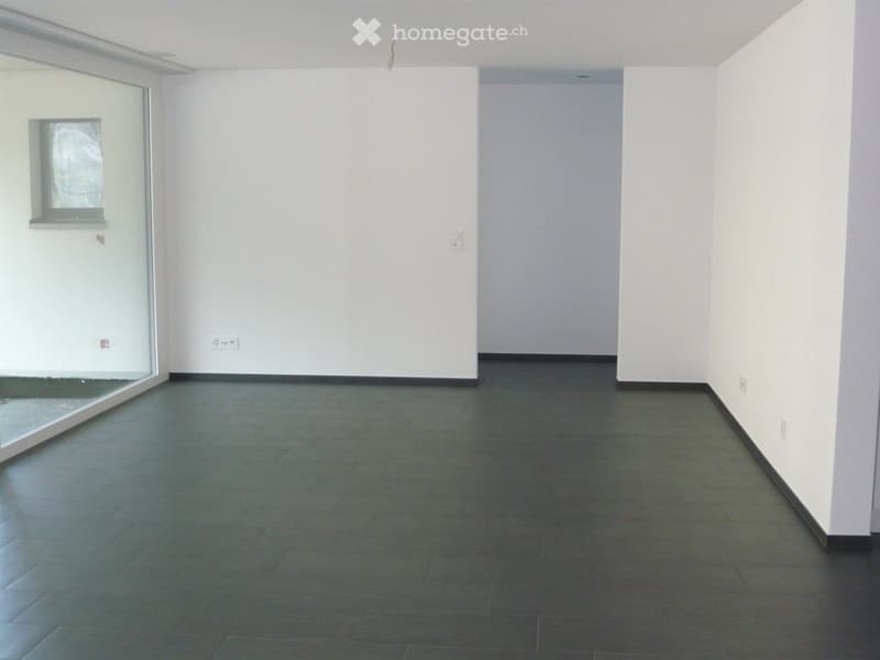 Empty room with white walls, dark tiled floor, and a large window with a glass door.