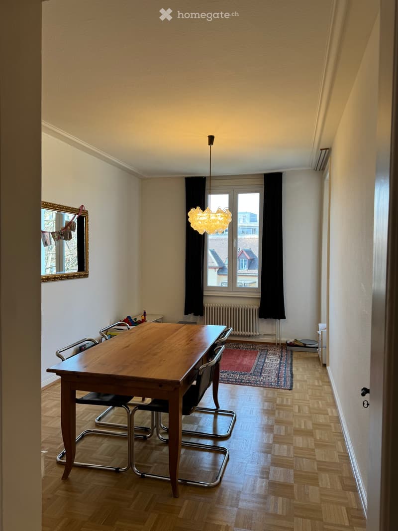 Dining room with wooden table, chairs, mirror, lamp, radiator, and rug.