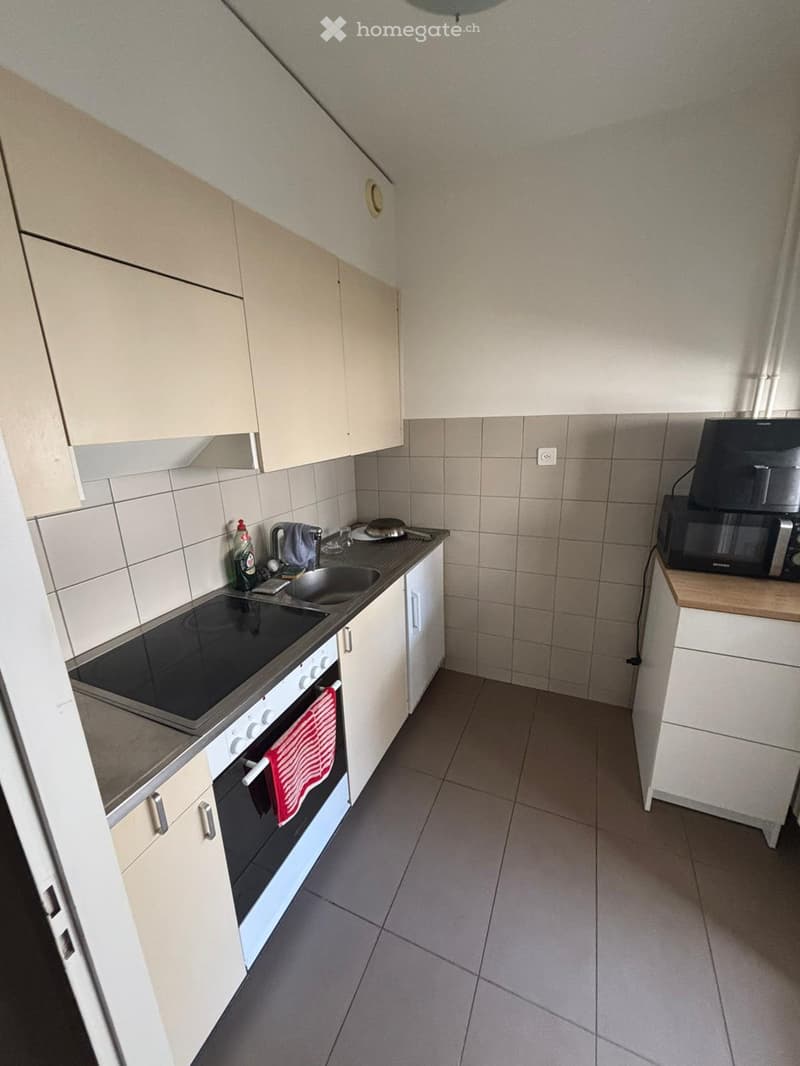 Modern kitchen with white cabinets, stainless steel appliances, and tiled backsplash. Features an oven, microwave, sink, and countertop items.