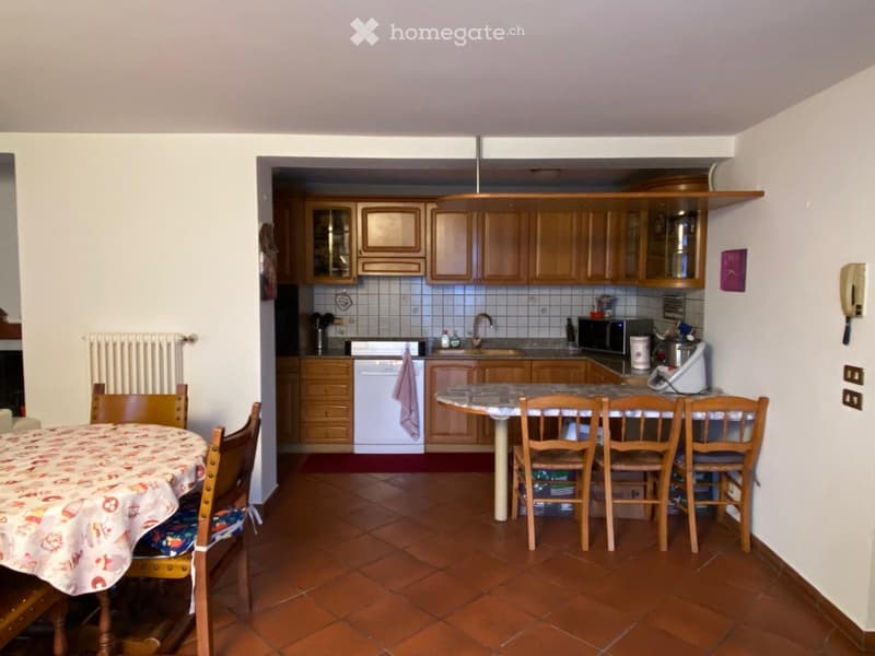 A combined dining and kitchen area with wooden cabinets, a dining table with chairs, and a kitchen counter with appliances.