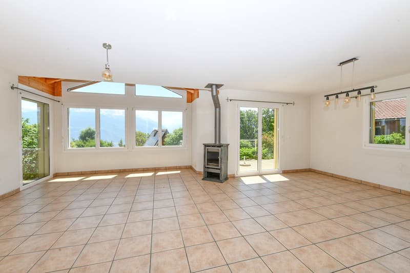 Empty room with tiled floor, large windows, skylights, and a wood-burning stove. No furniture or equipment present.