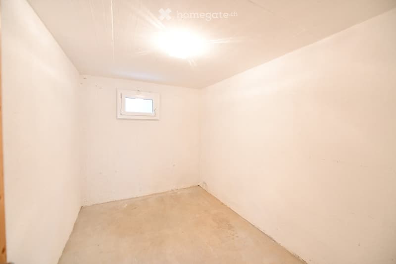 Empty room with white walls, concrete floor, and a small window with white frame. No furniture or equipment present.
