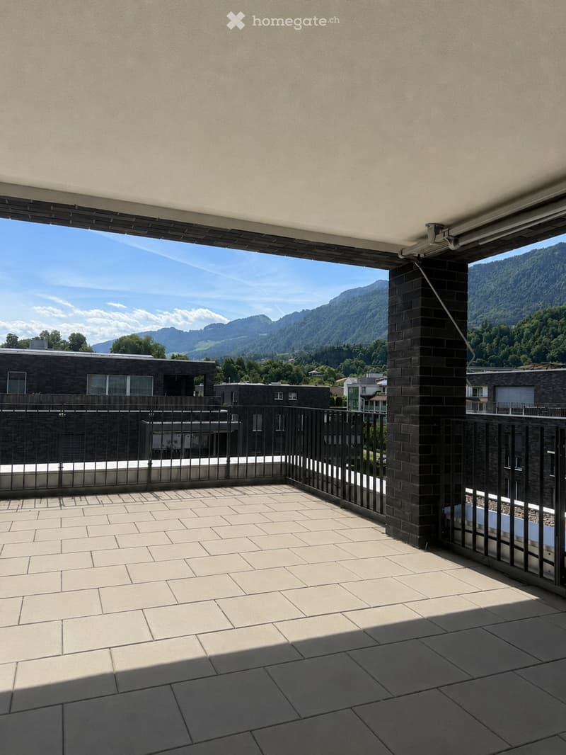 Balcony with tiled floor, metal railing, and scenic mountain view in the background.