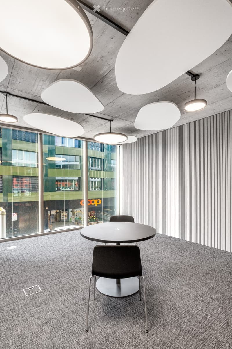 Round table, black chairs, large oval lighting fixtures, striped walls, large windows, grey carpet