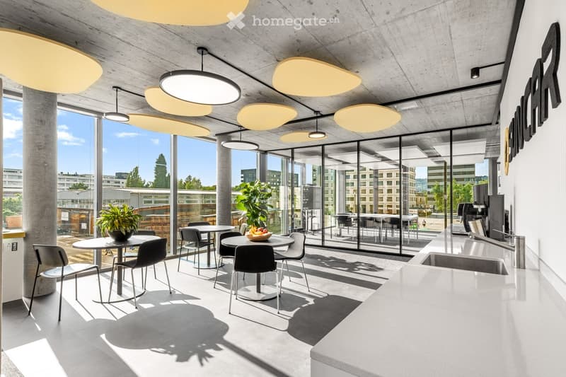 modern design with large windows, several tables and chairs, potted plants, kitchen area with a sink
