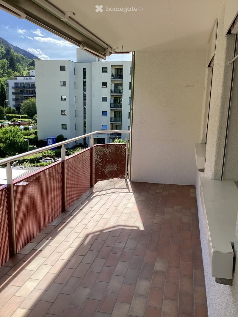 Balcony with tiled floor, metal railing, and scenic mountain view in the background.