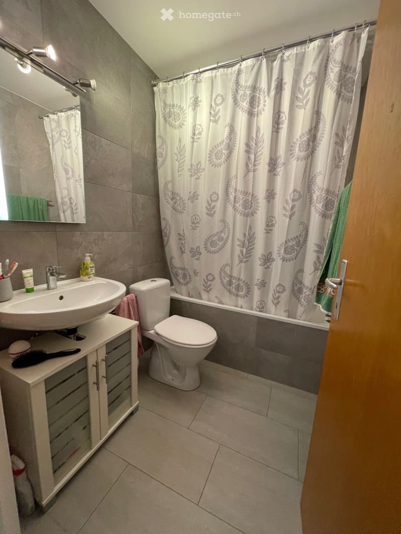 white tiled bathroom with sink, toilet, and bathtub