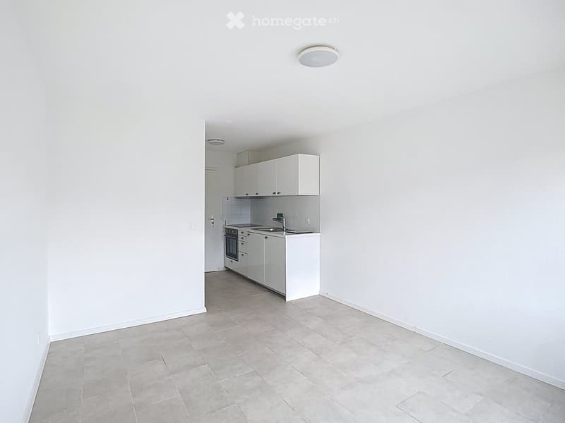Empty kitchen area with white cabinets, stainless steel sink, and tiled floor.