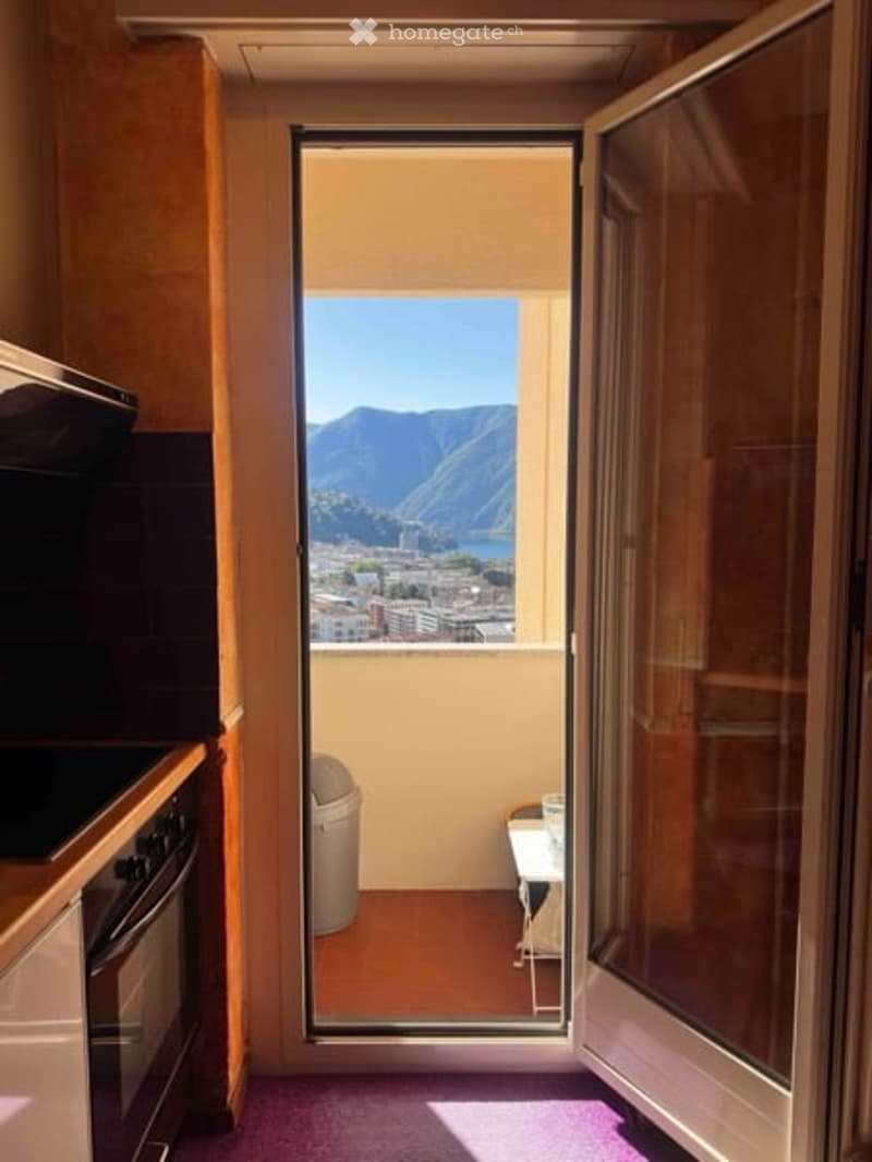 Balcony with a scenic mountain and lake view, accessible from a kitchen area with modern appliances.