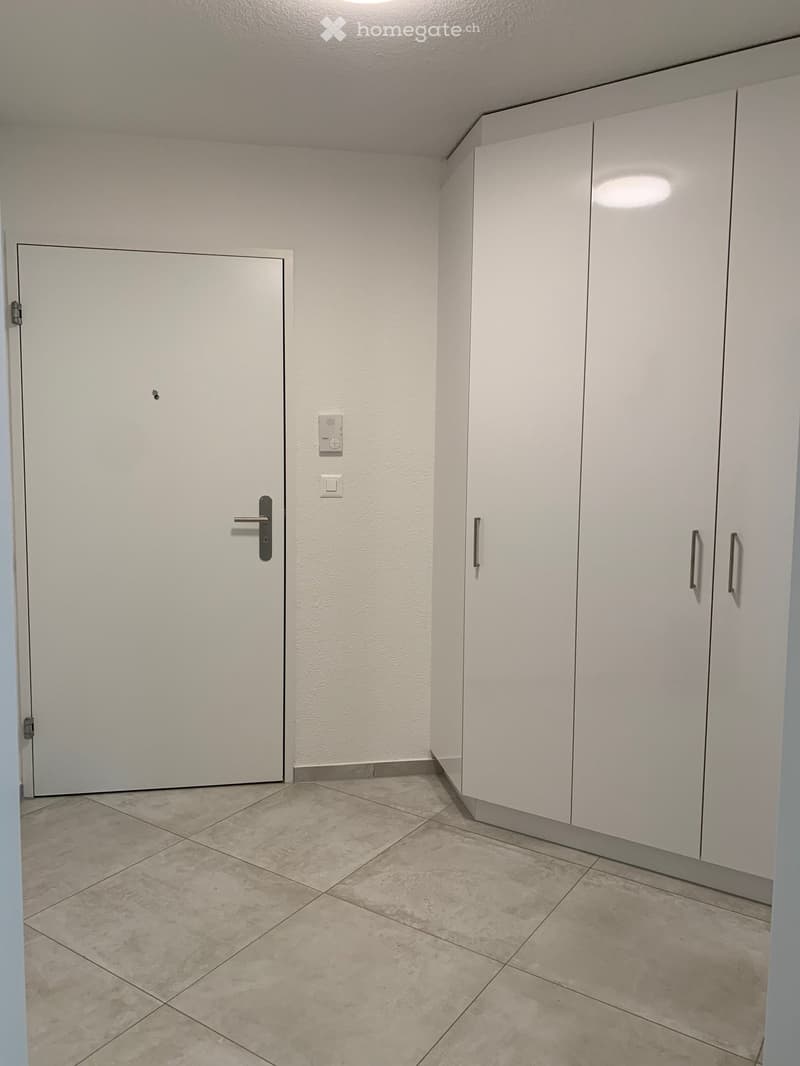 Entrance hallway with tile floor and white closets, a door with a lock and switch