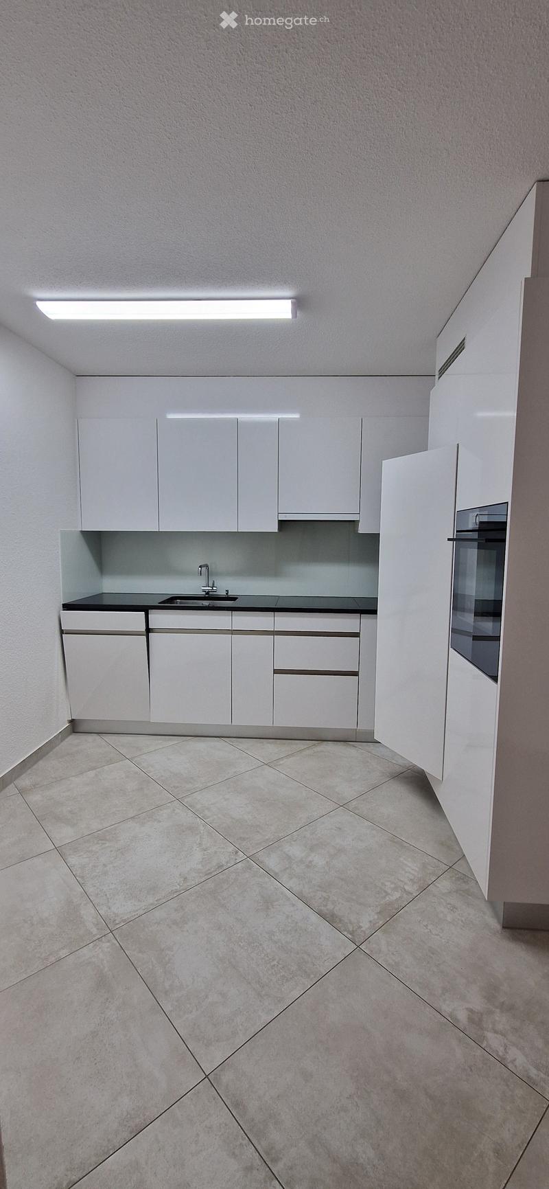 Modern kitchen with white cabinets, black countertops, stainless steel sink, and integrated appliances