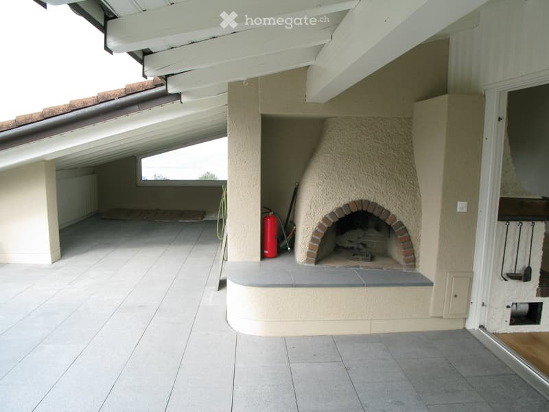 Outdoor area with a built-in brick fireplace, tiled floor, and a red fire extinguisher nearby.