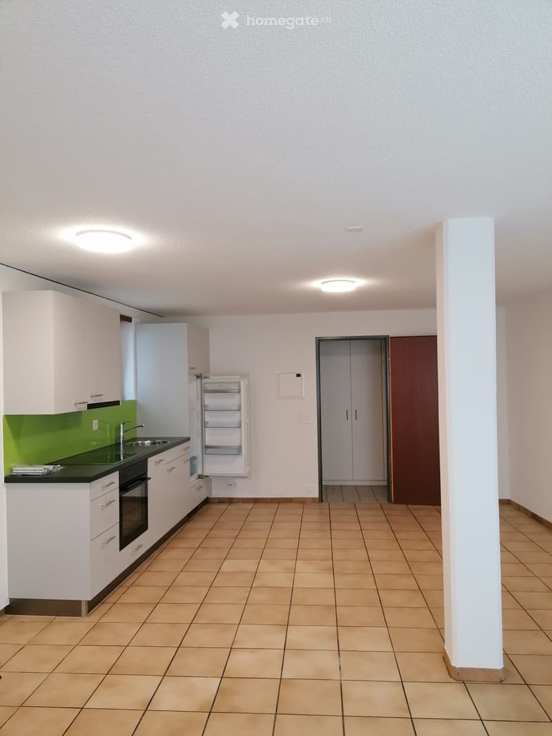 Modern kitchen with white cabinets, green backsplash, tiled floor, and built-in appliances including a sink, oven, and refrigerator.