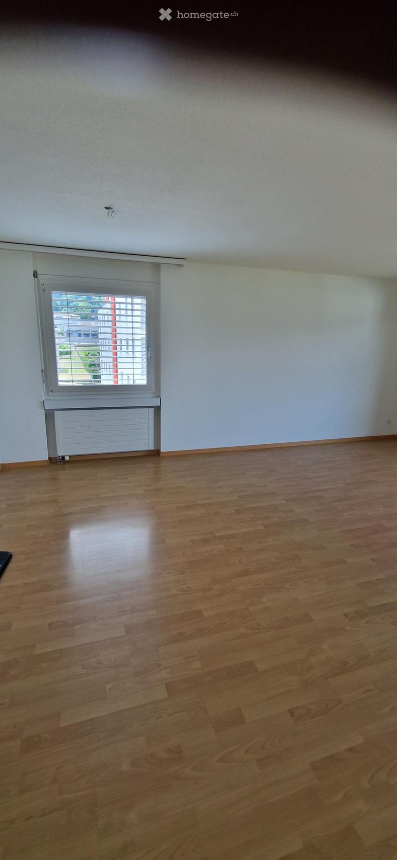 Empty room with wooden flooring, white walls, and a window with blinds. No furniture or equipment is present.