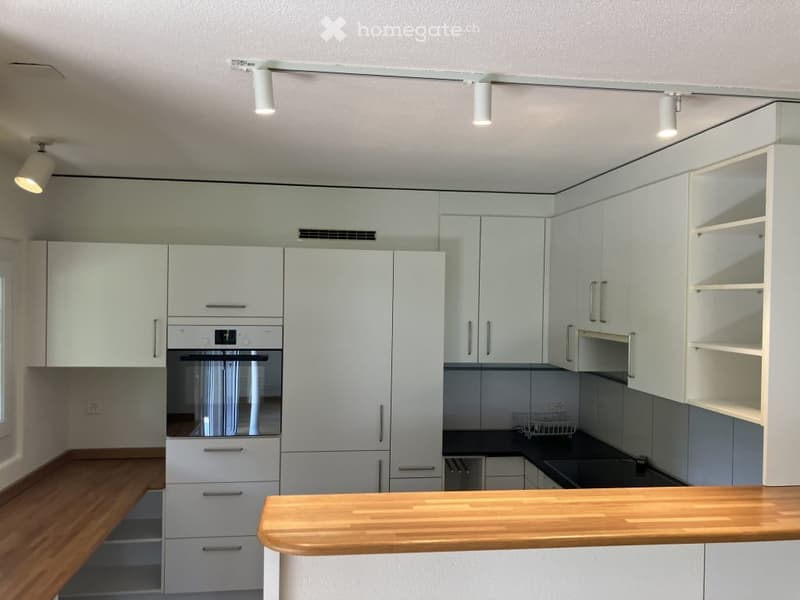 Modern kitchen with white cabinets, wooden countertop, built-in oven, and sleek design.