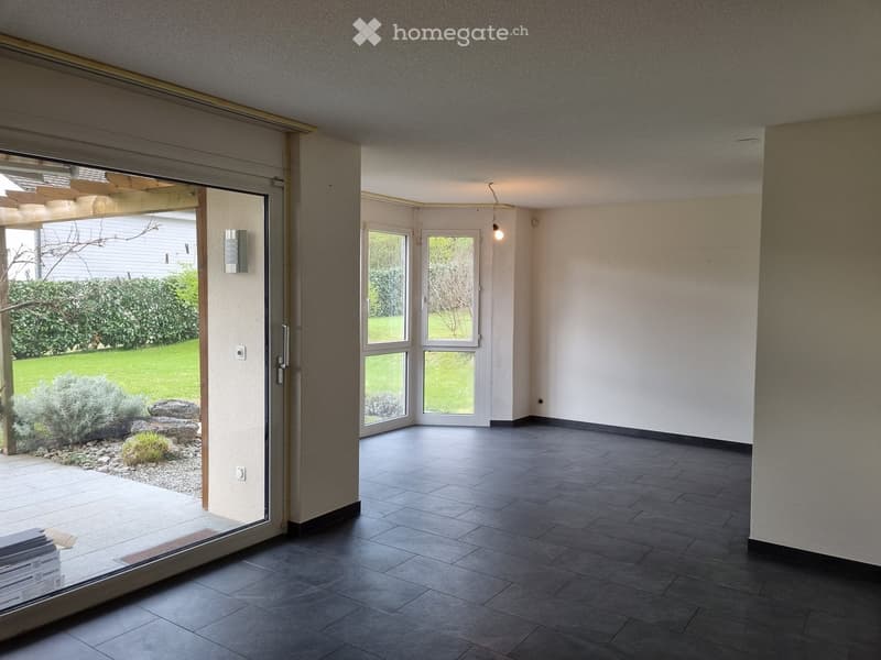 Empty room with dark tiled floor, large windows, and sliding glass doors leading to an outdoor area.