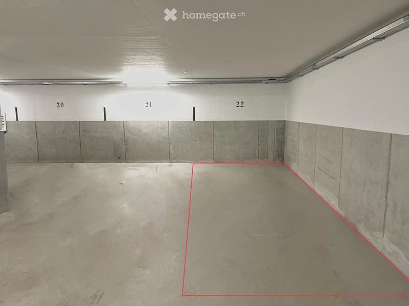Empty underground parking space with concrete floors and walls, marked with numbered sections.