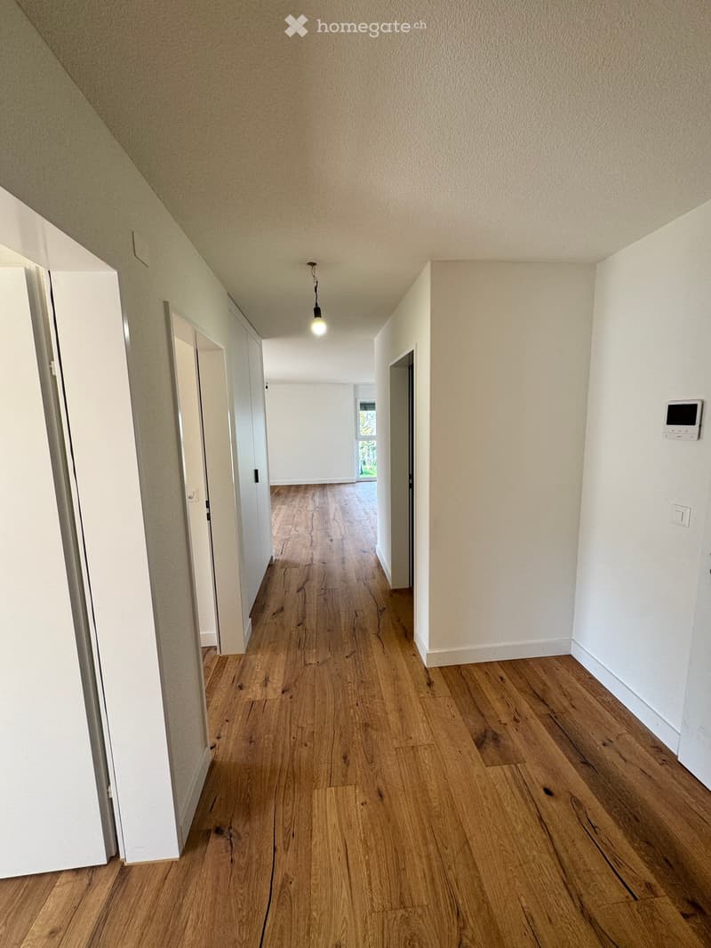 wooden floor, white walls, ceiling light, doors on both sides