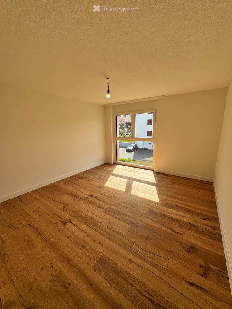 empty room, hardwood floors, large window, view of parking lot