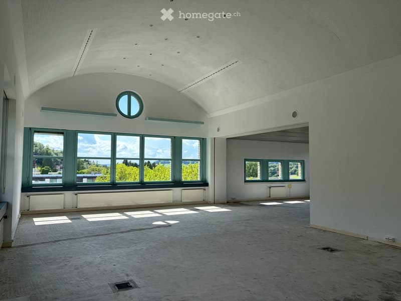 Empty room with concrete floor, white walls, large windows, and radiators. No furniture or equipment present.