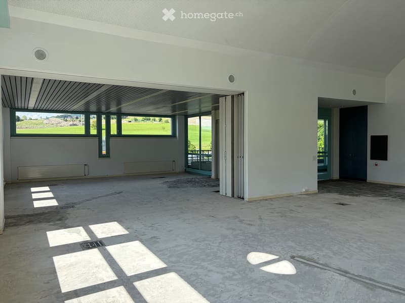 Empty room with concrete floor, white walls, large windows, and a door leading to an outdoor area.