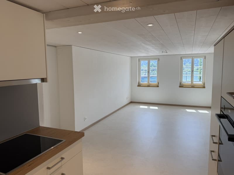 Modern kitchen with white cabinets, wooden countertop, and built-in stove. Features large windows and a sleek, minimalist design.