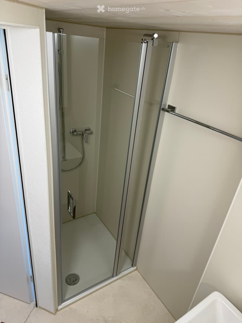 Modern shower enclosure with glass doors, chrome fixtures, and a sleek design.