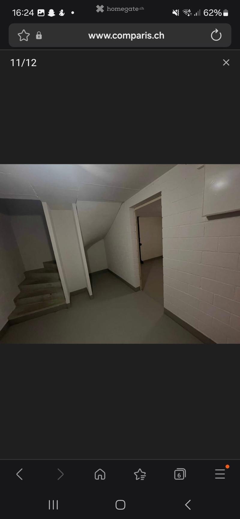 Empty hallway with white brick walls, a staircase leading upwards, and a door at the end.