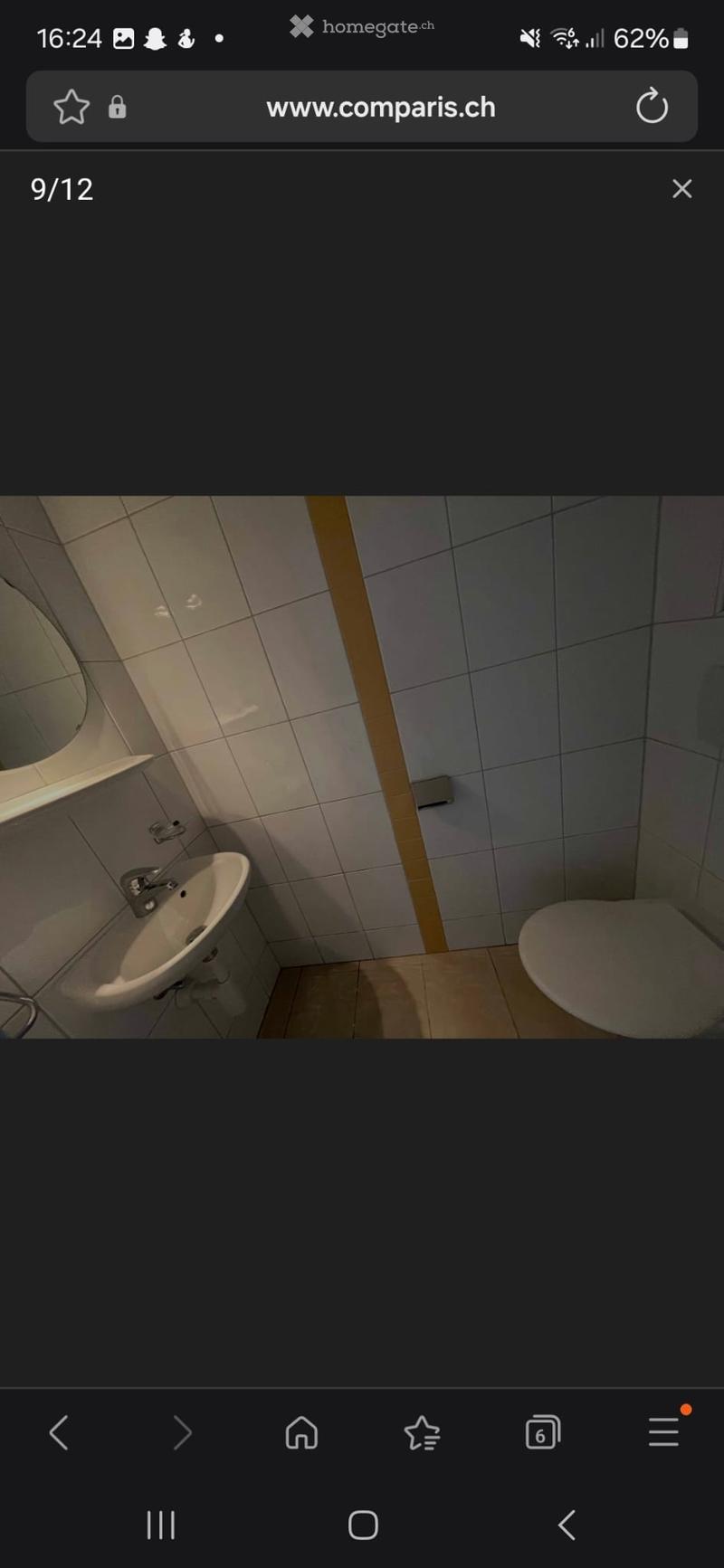 Small bathroom with a white sink, faucet, and toilet. The walls are tiled in light gray and white, and the floor is tiled in a light brown color.