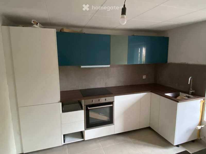 Modern kitchen with white and blue cabinets, a dark countertop, an oven, a sink, and a faucet.