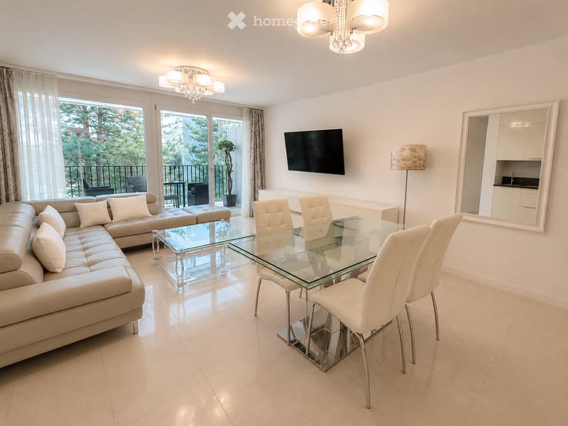 Modern living and dining area with a beige leather sofa, glass dining table with white chairs, floor lamp, TV, and access to a balcony.