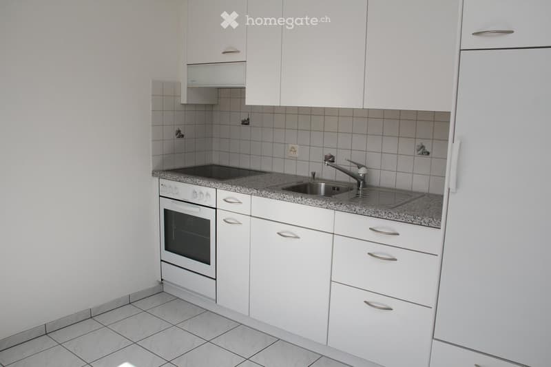 Modern kitchen with white cabinets, granite countertop, stainless steel sink, and built-in oven.