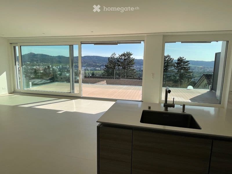 Modern kitchen with large windows offering a scenic view, featuring a sink and faucet.