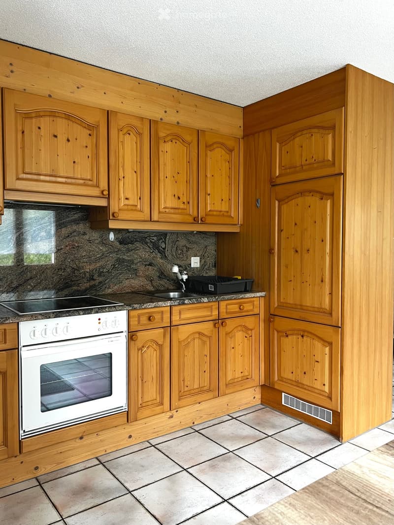A small kitchen with wooden cabinets, a white oven, a sink with a faucet, and granite countertops.
