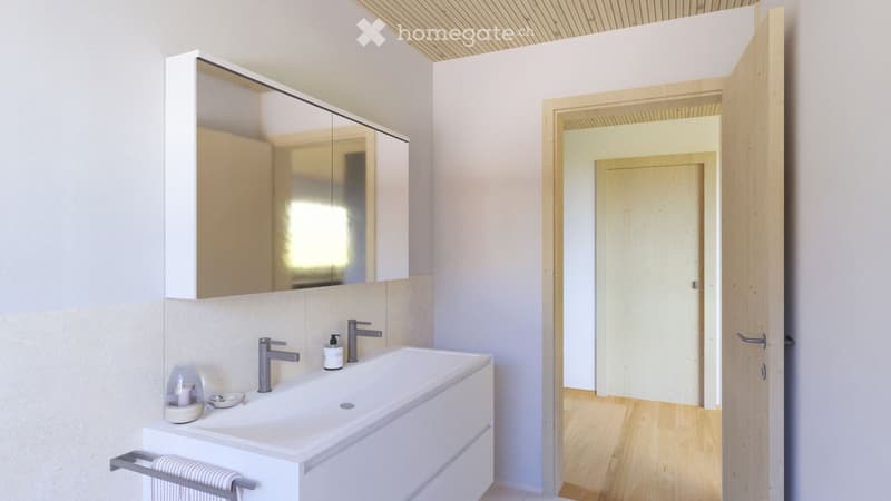 Modern bathroom with a white sink, two faucets, a large mirror cabinet, and a towel rack with a towel. The room features light-colored walls and wooden flooring.
