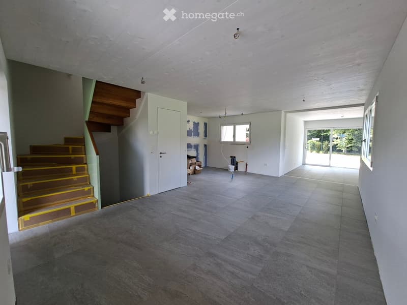 Unfurnished Room. Empty room with grey tiled floor, white walls, staircase leading upwards, and a large window letting in natural light.