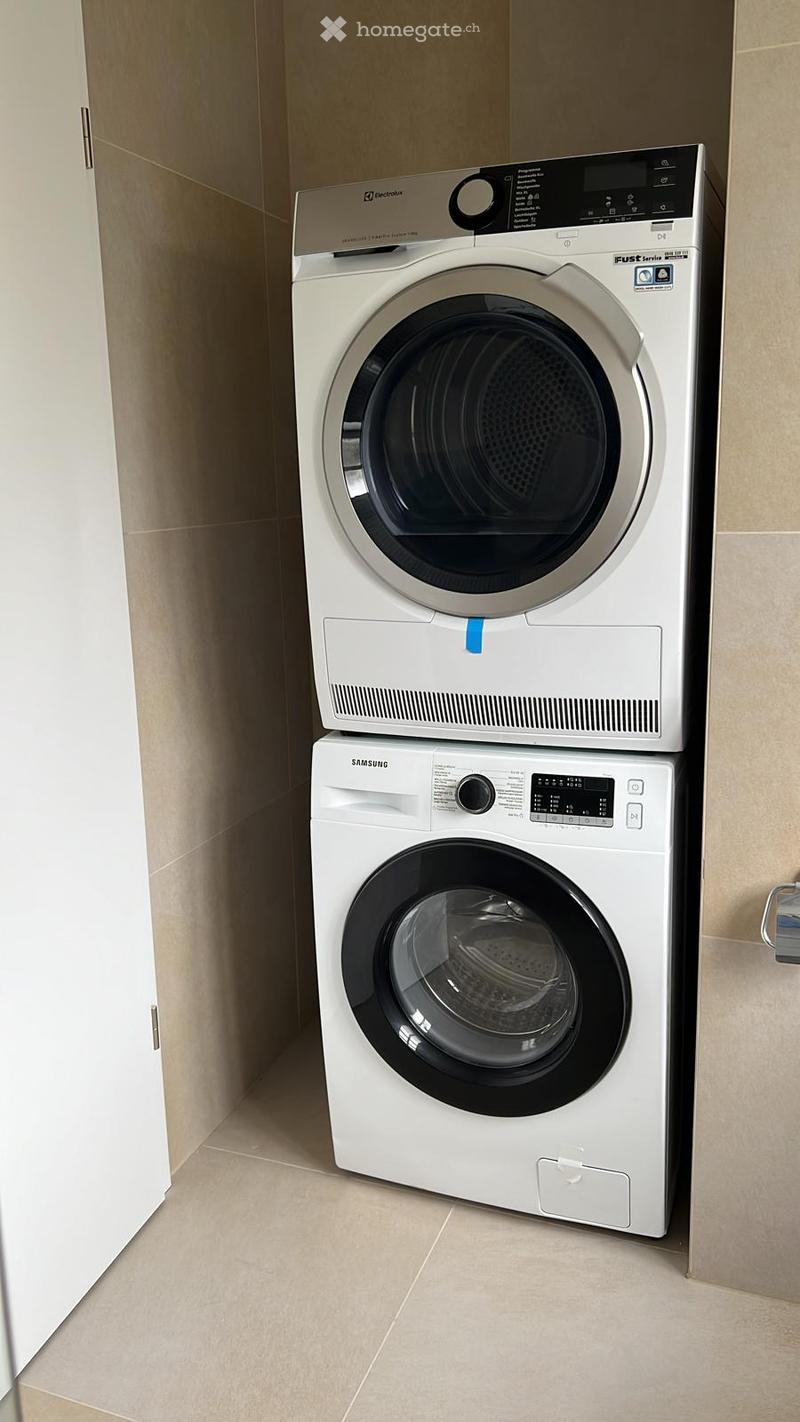 A laundry room with a Samsung washing machine and a dishwasher stacked on top of each other